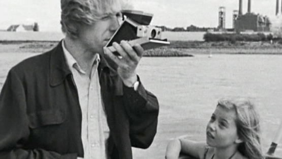 Un hombre saca una foto en un bote mientras una niña lo mira.