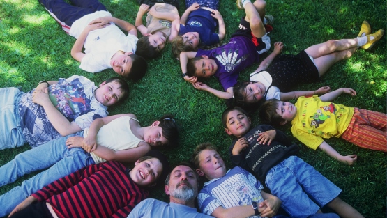 Un profesor y sus niños recostados en círculo en el pasto mirando el cielo